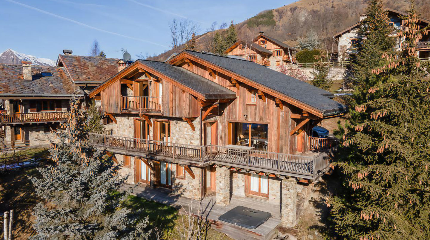 Gros plan sur un détail architectural en bois ancien d'un chalet savoyard traditionnel avec texture visible et arrière-plan flouté